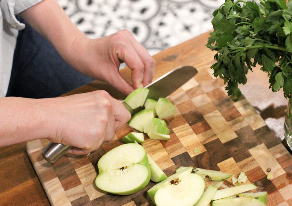 close up picture of woman cutting apples on a cutting board