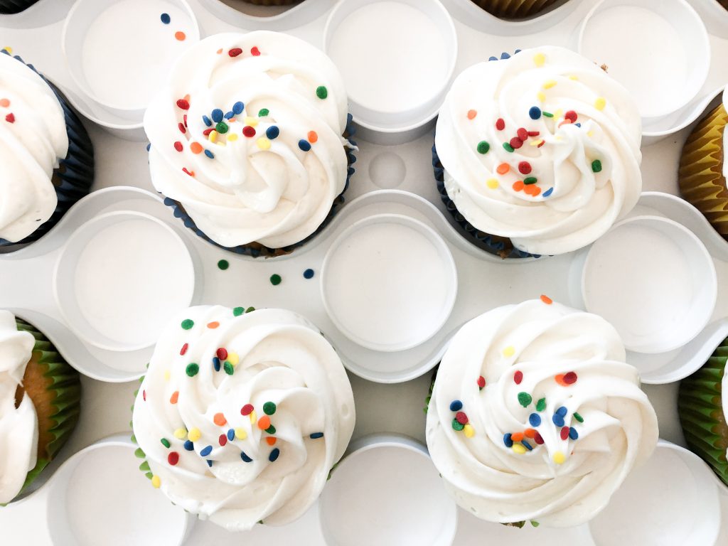 close up of white cupcakes with primary color sprinkles.