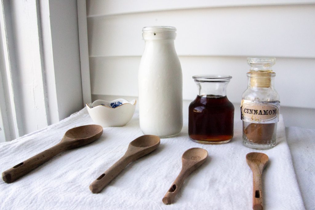 iced coffee ingredients and wooden spoons sitting on a table with a white table cloth. 