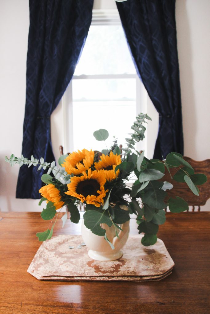 sunflower bouquet on a antique wood table with navy blue curtains in the background