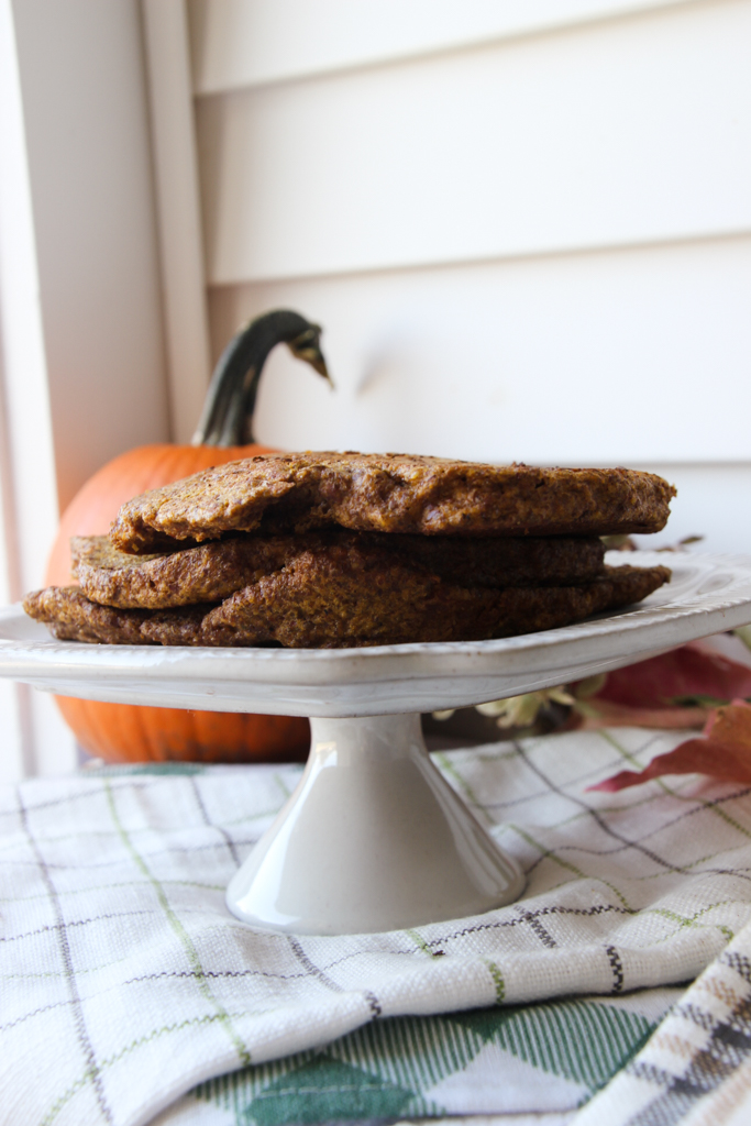 flaxseed pumpkin pancakes on a white display tray with a pumpkin in the background