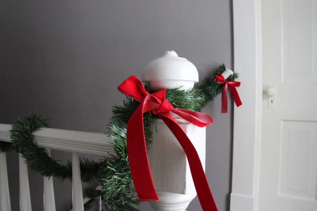 Red ribbon tied on garland and around a white banister